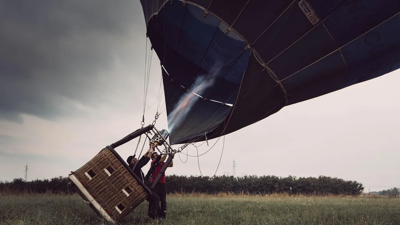 Équipe au sol qui gonfle le ballon d’une montgolfière avant le départ