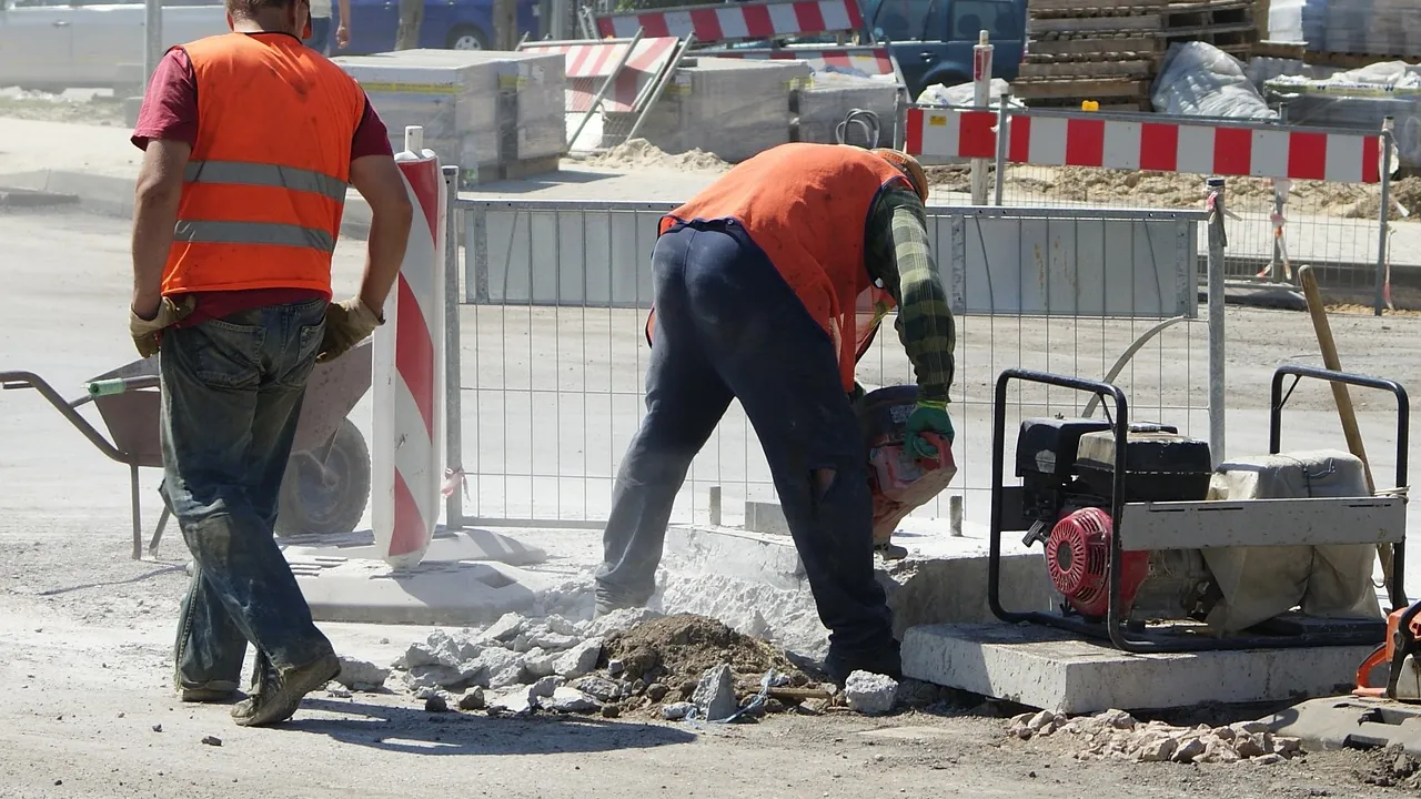 Ouvriers en gilet orange qui réparent une chaussée